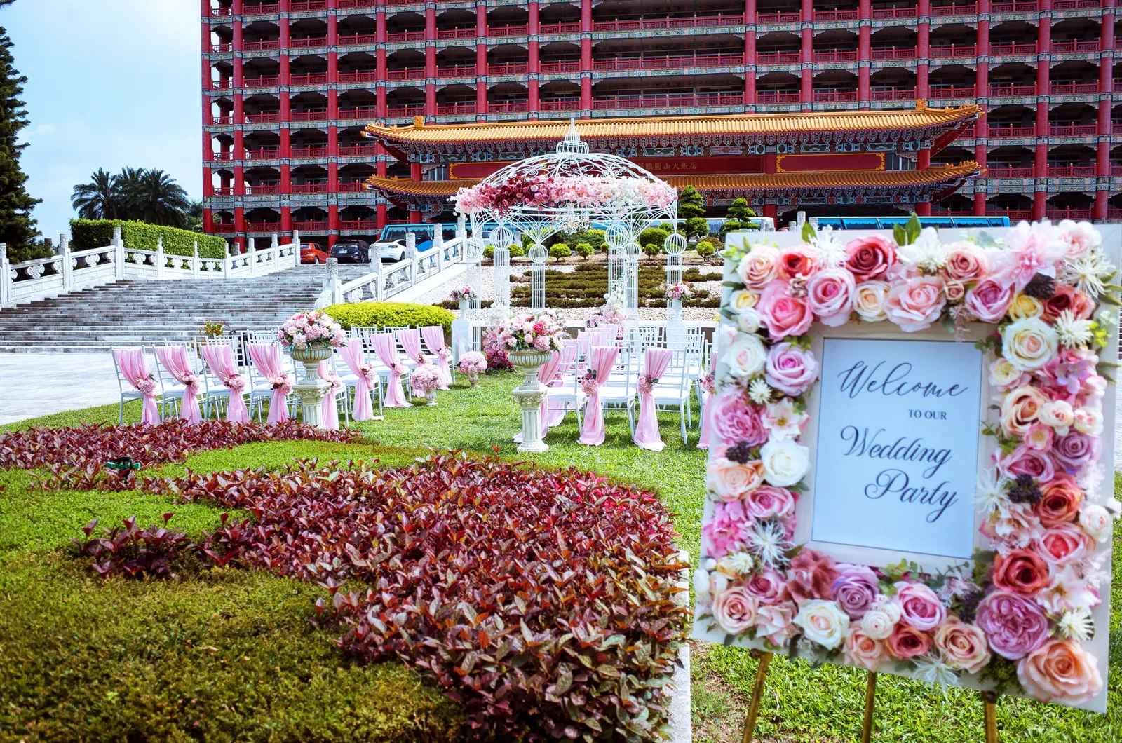玫瑰花框迎賓牌 Welcome to Our Wedding Party,背景為拱門走道與紅金建築