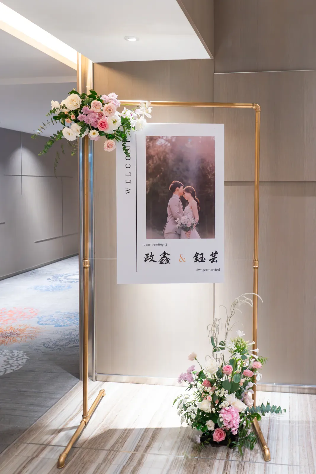 迎賓立牌印新人政鑫與鈺芸婚紗照，金架綴粉白花束