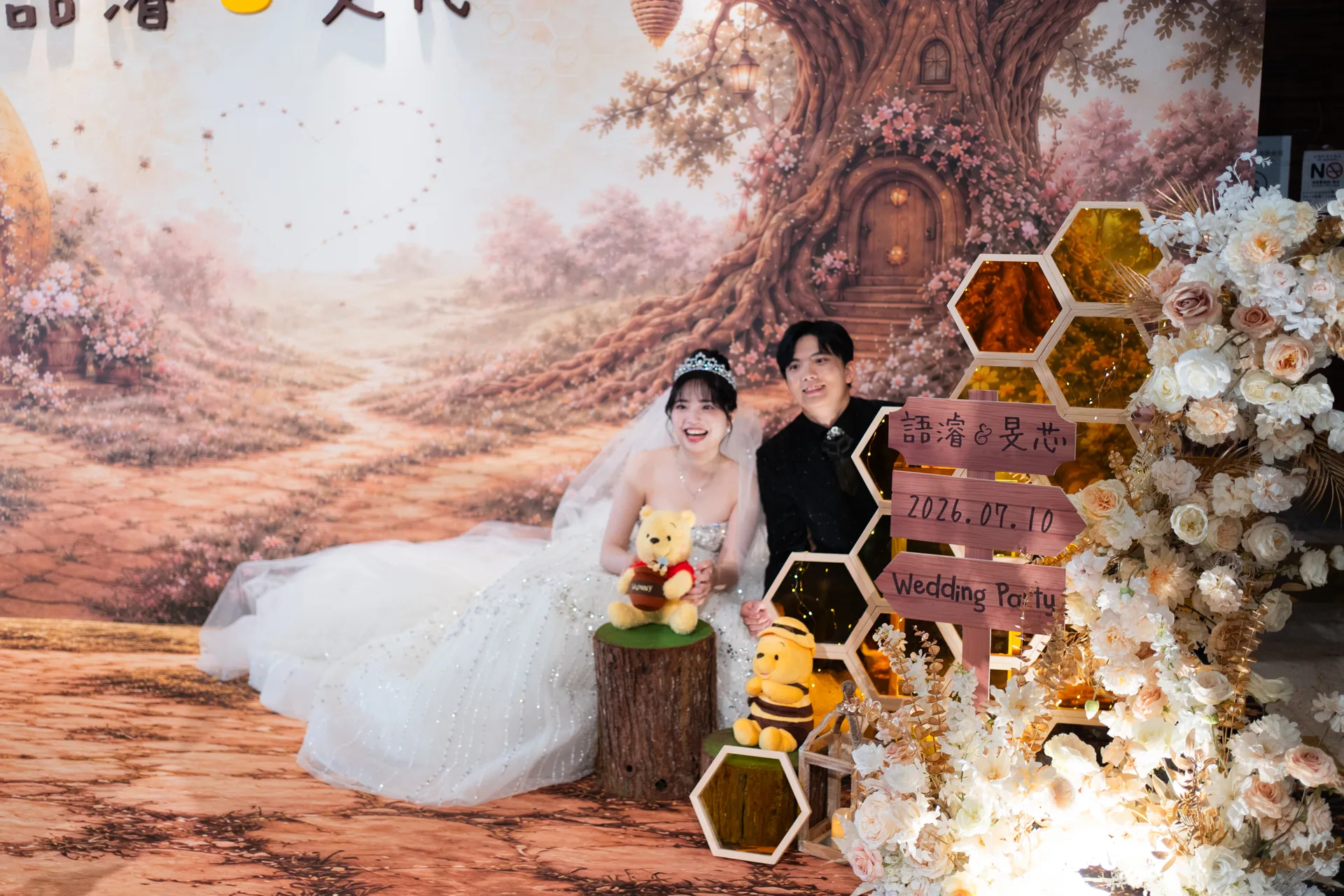 新人坐在琥珀色六角壓克力蜂巢展示櫃與婚禮日期牌旁,大直典華花田盛事廳小熊維尼主題婚禮