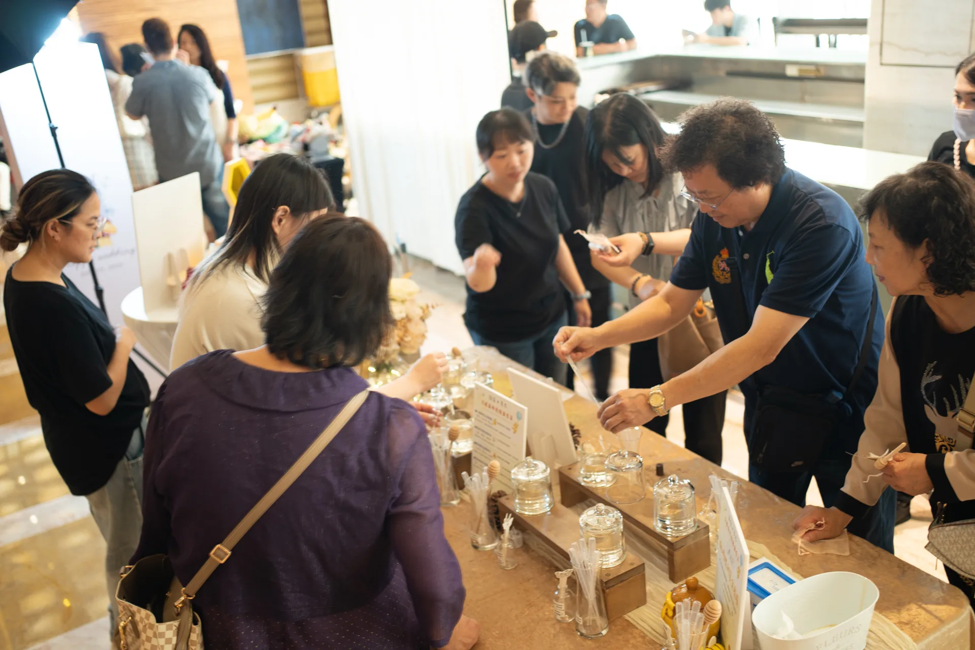 長輩賓客圍在婚禮精油調香桌前，手持滴管與聞香棒動手調配專屬香氣