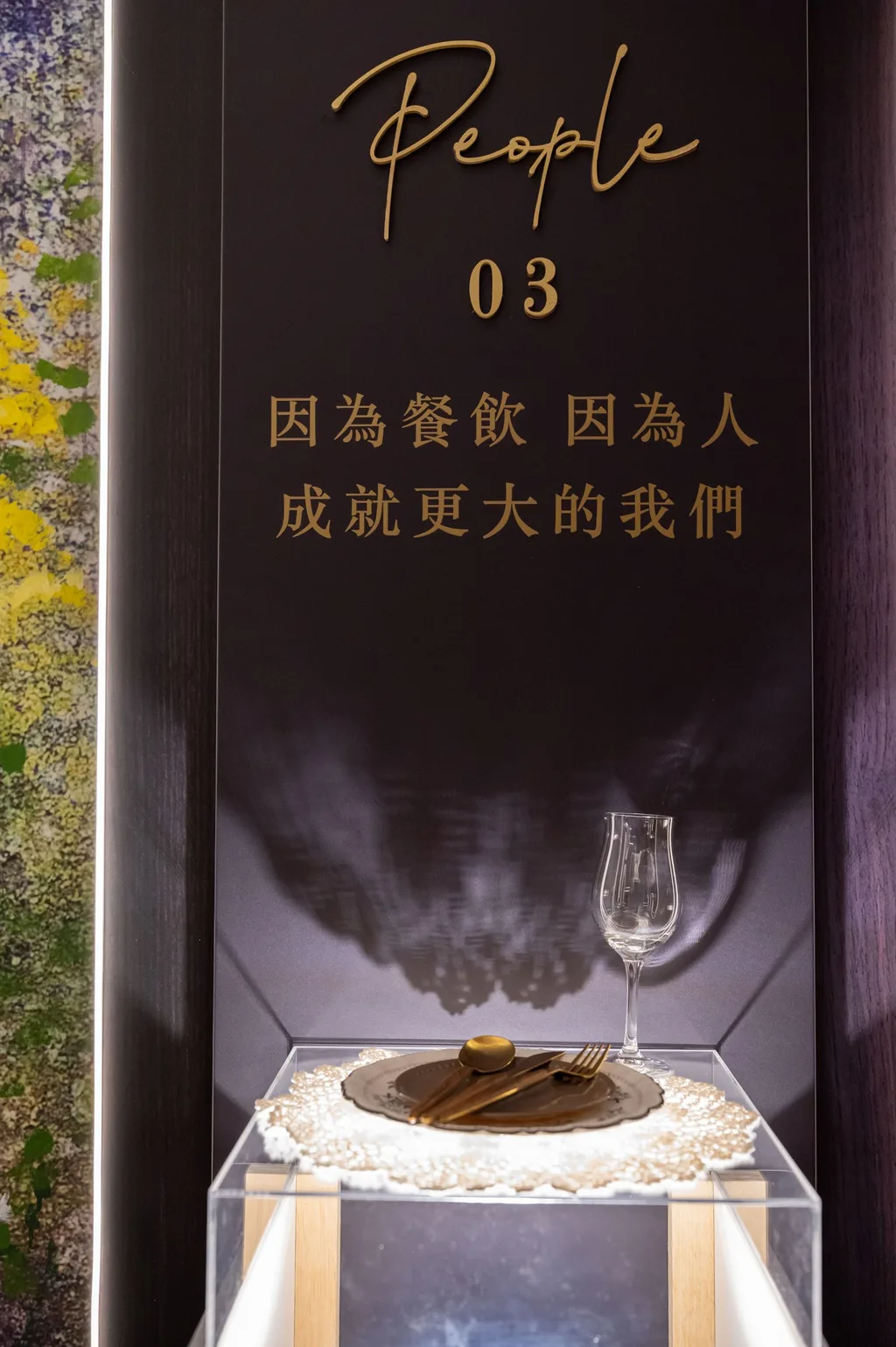 光的軌跡 03 People 看台，壓克力罩裡的餐盤與酒杯，看台上寫著「因為餐飲 因為人 成就更大的我們」，台大明達館生日派對