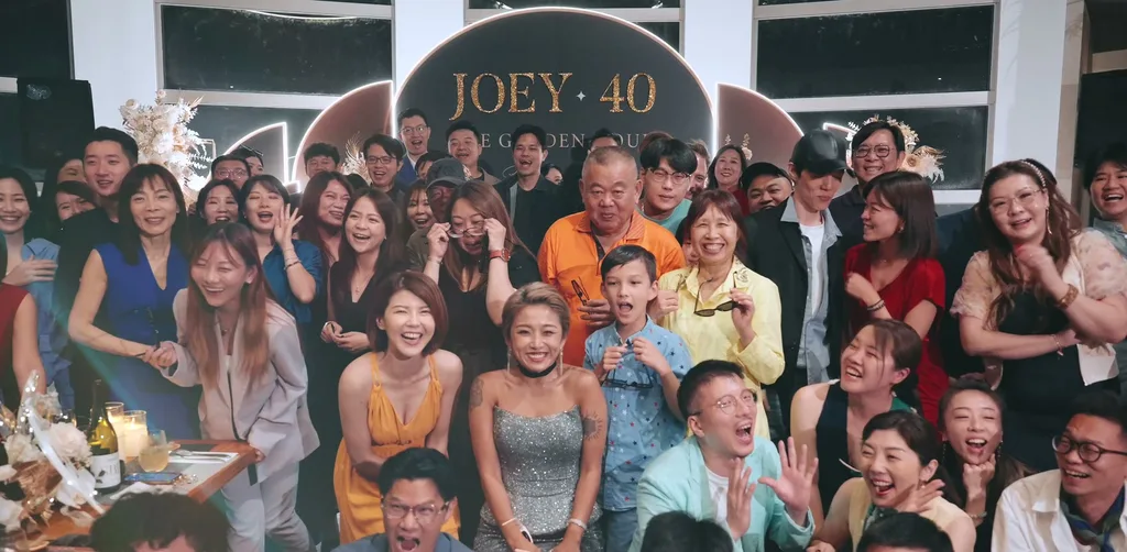JOEY 40 生日派對全場百人大合照,賓客坐滿長桌與前排地板,背景是拱形主背板與乾燥花,台大明達館 MD 創作料理