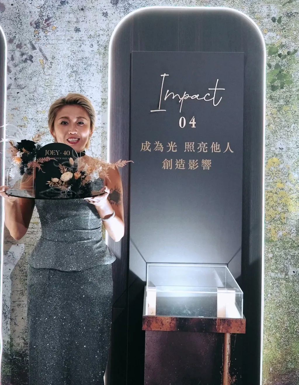 光的軌跡 04 Impact 看台,壽星雙手捧著舞台縮小版,圓拱造型上有 JOEY 40 字樣與乾燥花,看台上寫著「成為光 照亮他人 創造影響」,派對結束後帶走留念