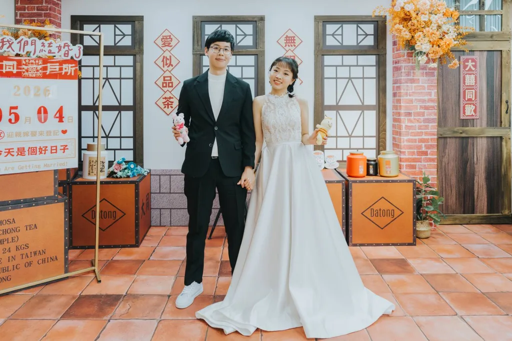 新人站在大同戶政結婚登記背板前，背景為紅磚柱、木格窗與茶箱道具