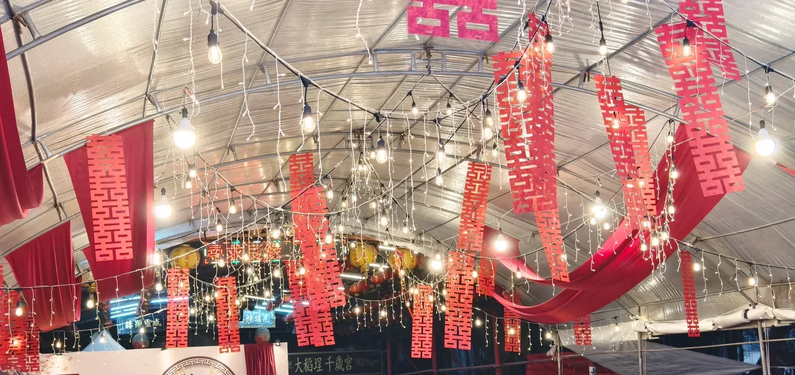傍晚的帳棚燈串、小軒窗背板與宮廟匾額同框
