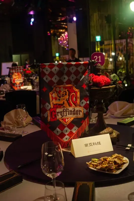深色餐桌上，葛來分多旗幟、紅花裝飾與酒杯，營造奇幻婚禮氛圍。