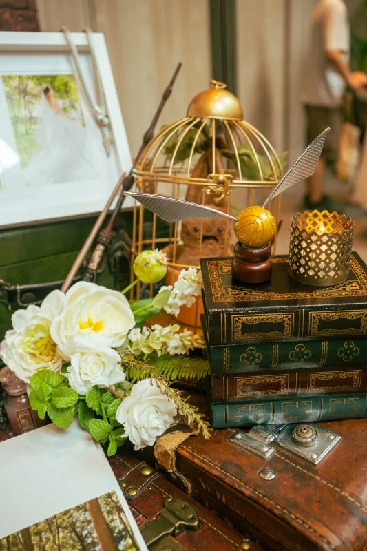 金色鳥籠、魔法書、飛天金探子與白花點綴，呈現奇幻復古婚禮佈置。