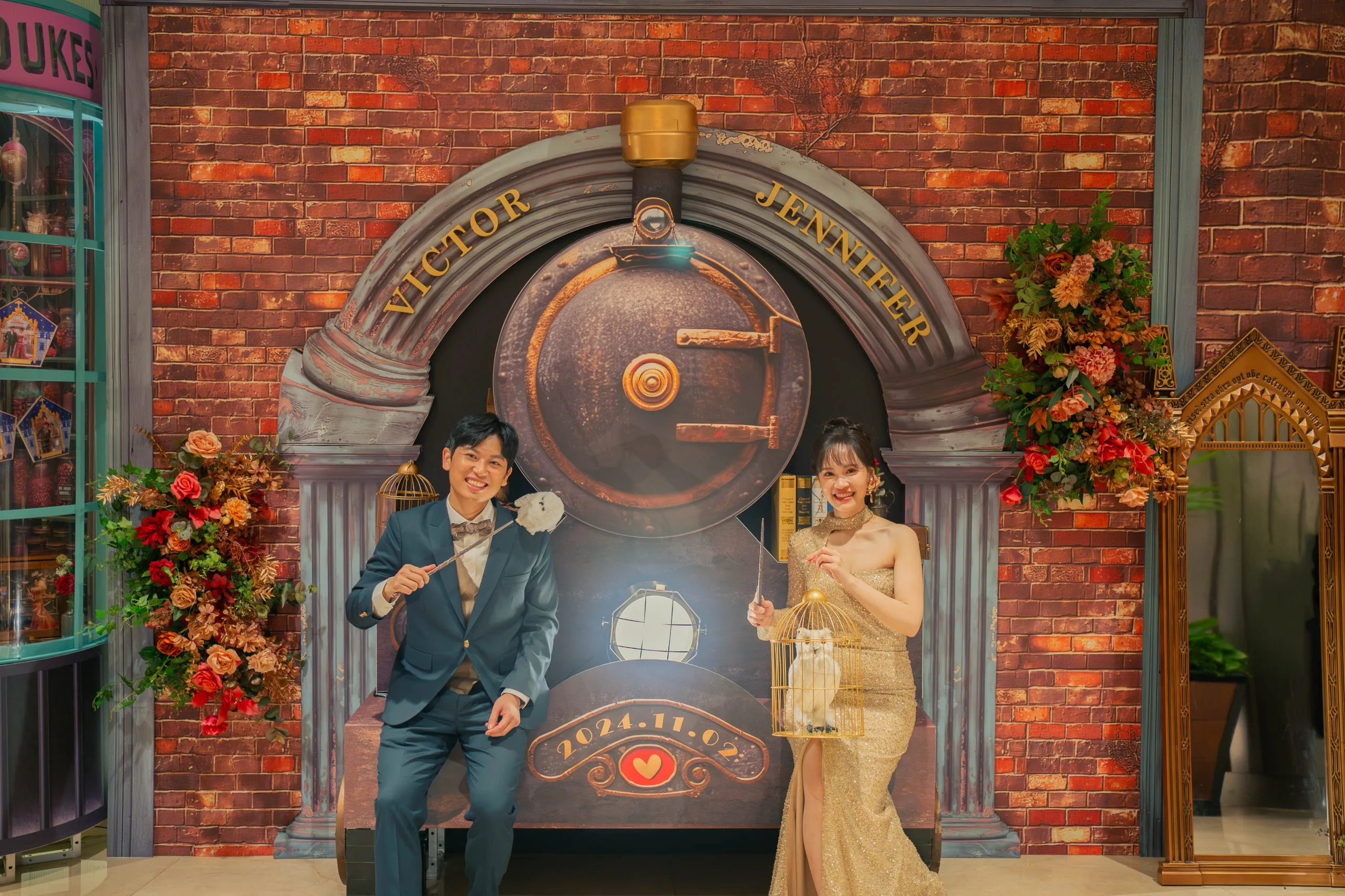 婚禮佈景前，新郎新娘於紅磚牆與金色火車頭裝飾旁，持貓頭鷹，氣氛溫馨浪漫。