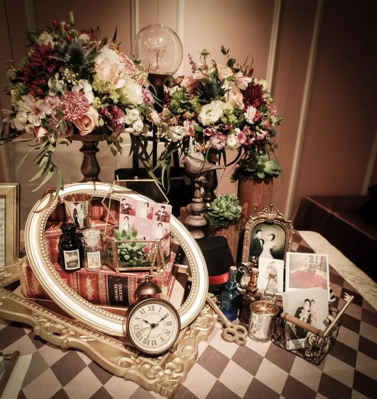 復古風婚禮佈置,鮮花、書籍、時鐘與新人照,溫馨浪漫。