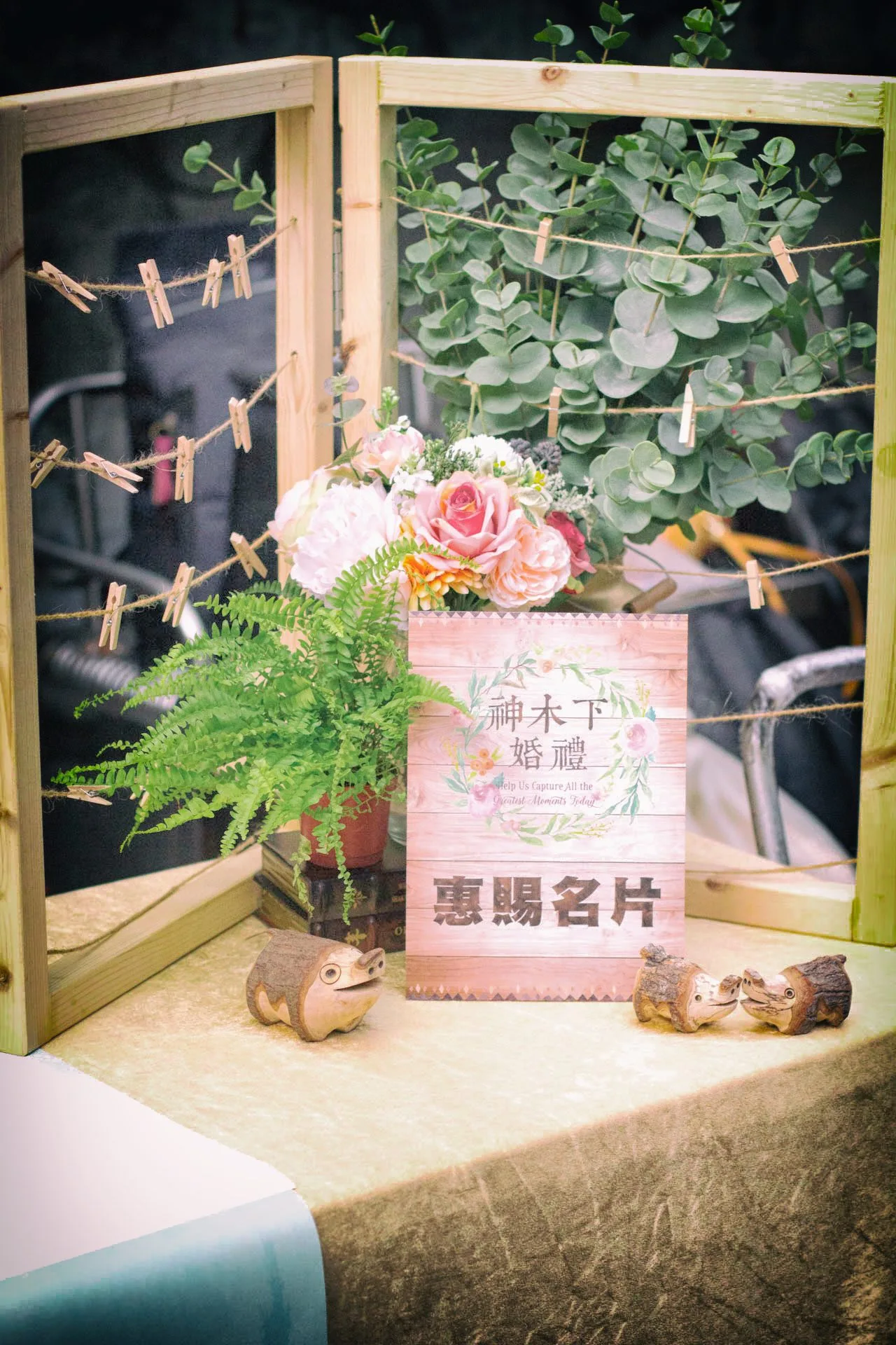 在充滿綠意的戶外婚禮場地,原木長桌上擺放著精緻的白綠色系花藝與典雅燭台,營造出清新自然且溫馨浪漫的優雅氛圍。