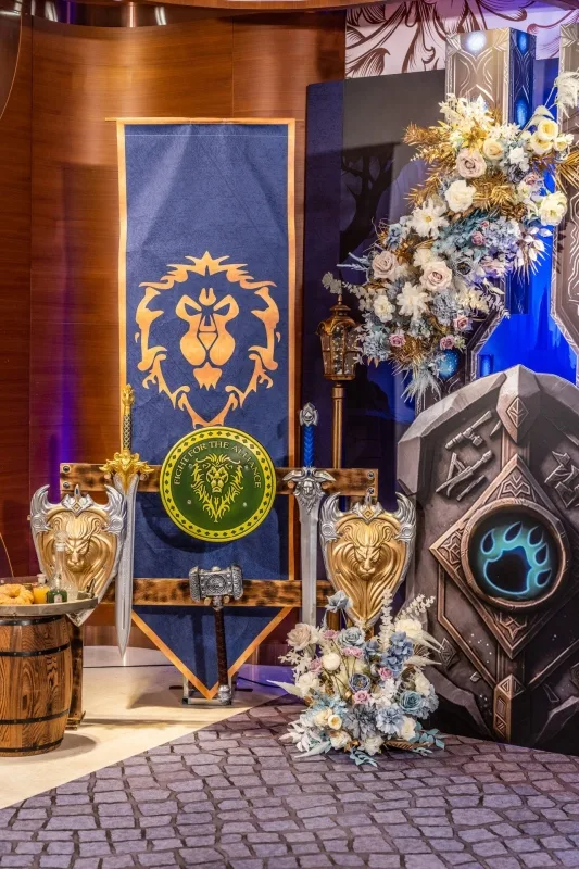 藍金魔獸聯盟主題婚禮佈置,含旗幟、劍盾、花藝,展現奇幻氛圍。