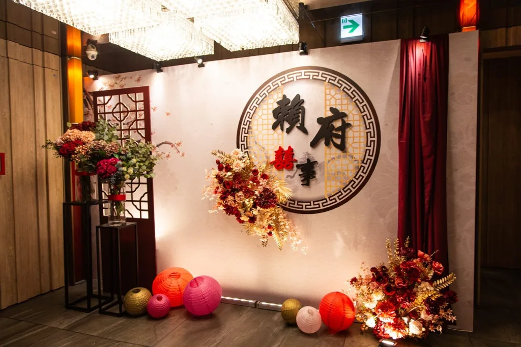 華麗中式婚宴佈置，紅金色花藝搭配「賴府囍事」圓牌與燈籠。