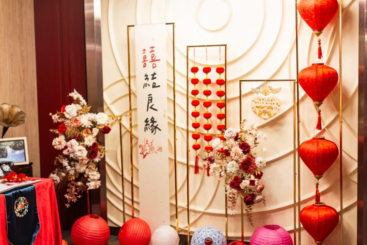 紅色燈籠、金邊囍字掛軸與粉紅花藝，佈置出喜氣洋洋的婚禮場景。