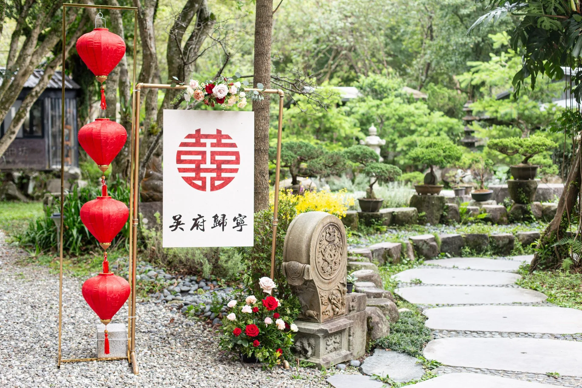 喜慶紅燈籠與雙喜字佈置的綠意庭園，點綴花藝及石雕，充滿傳統婚禮氛圍。