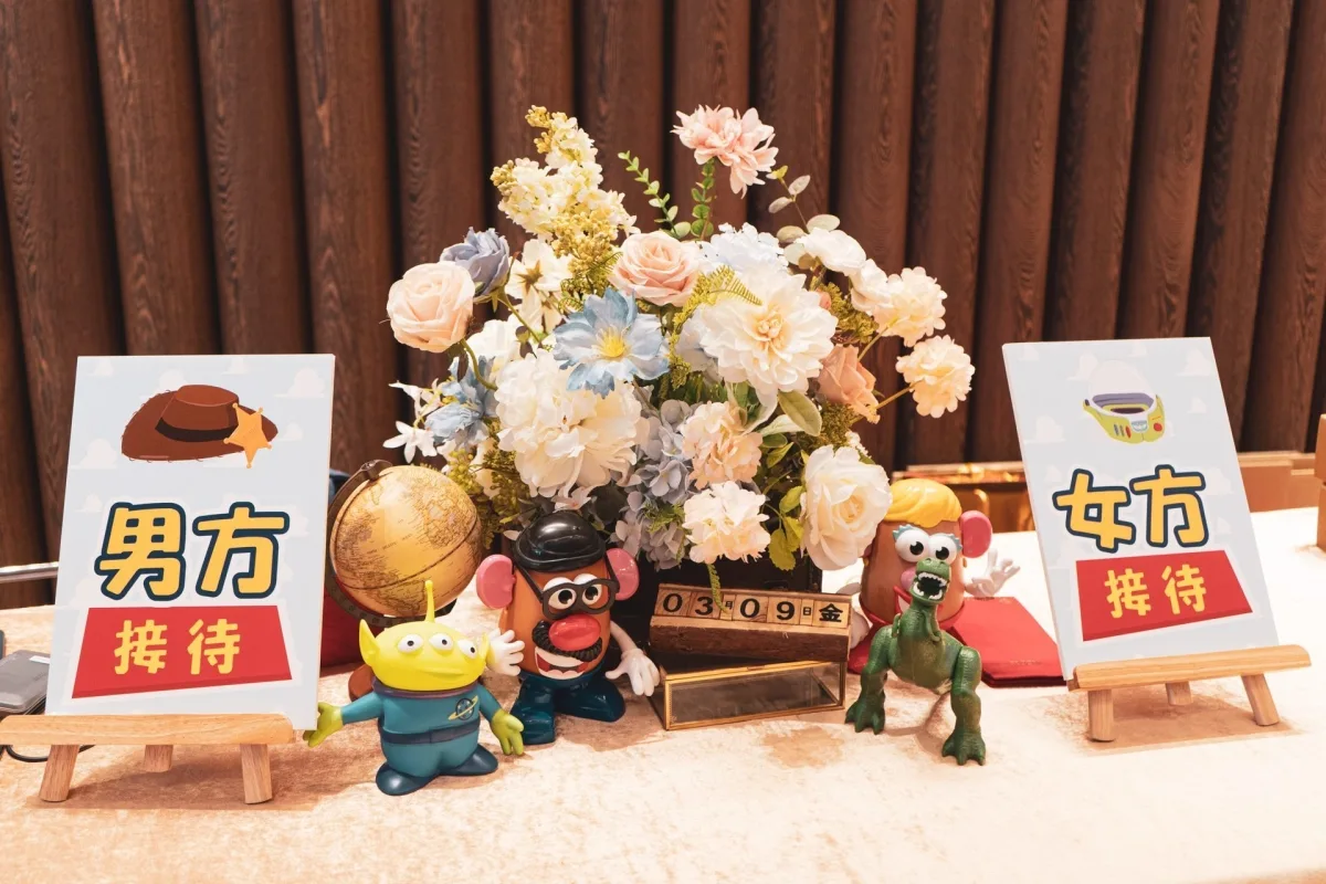 婚禮接待區,花束繽紛,搭配《玩具總動員》玩偶與主題指示牌,色調溫馨。