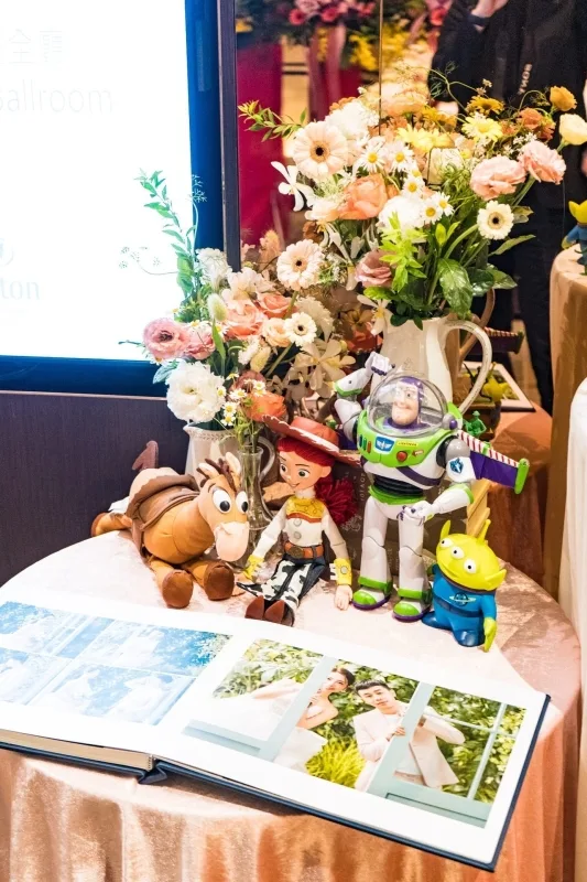 婚禮相簿、玩具總動員角色與柔和花藝裝飾，暖色調營造浪漫氣氛