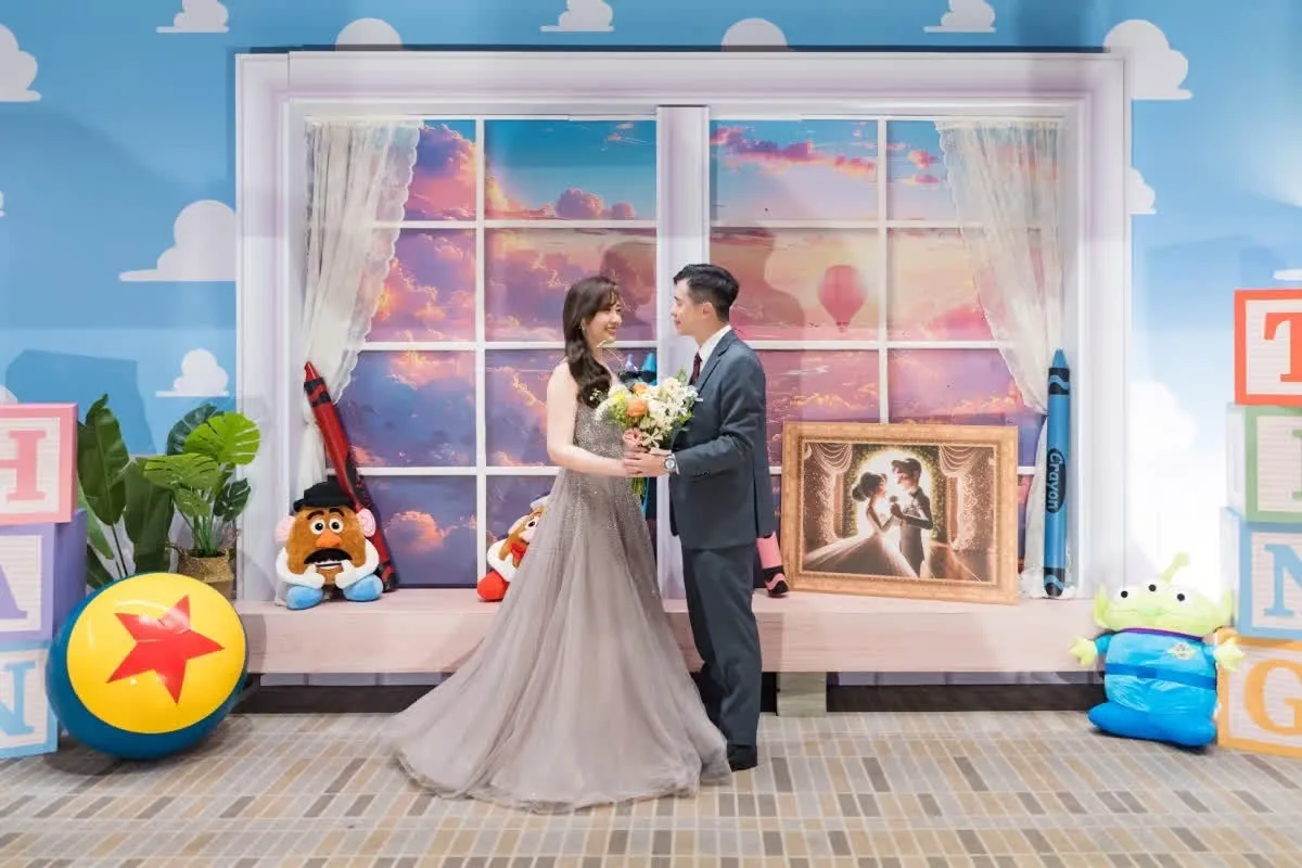 浪漫婚禮，新婚夫婦於繽紛玩具主題窗景前，手捧花束，背景彩霞滿天。