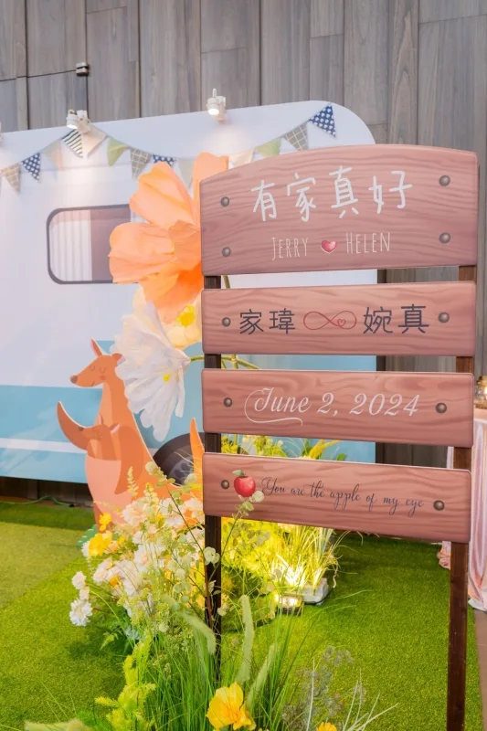 婚禮佈景有木牌、袋鼠、花草和露營車，綠草如茵，色調溫暖。