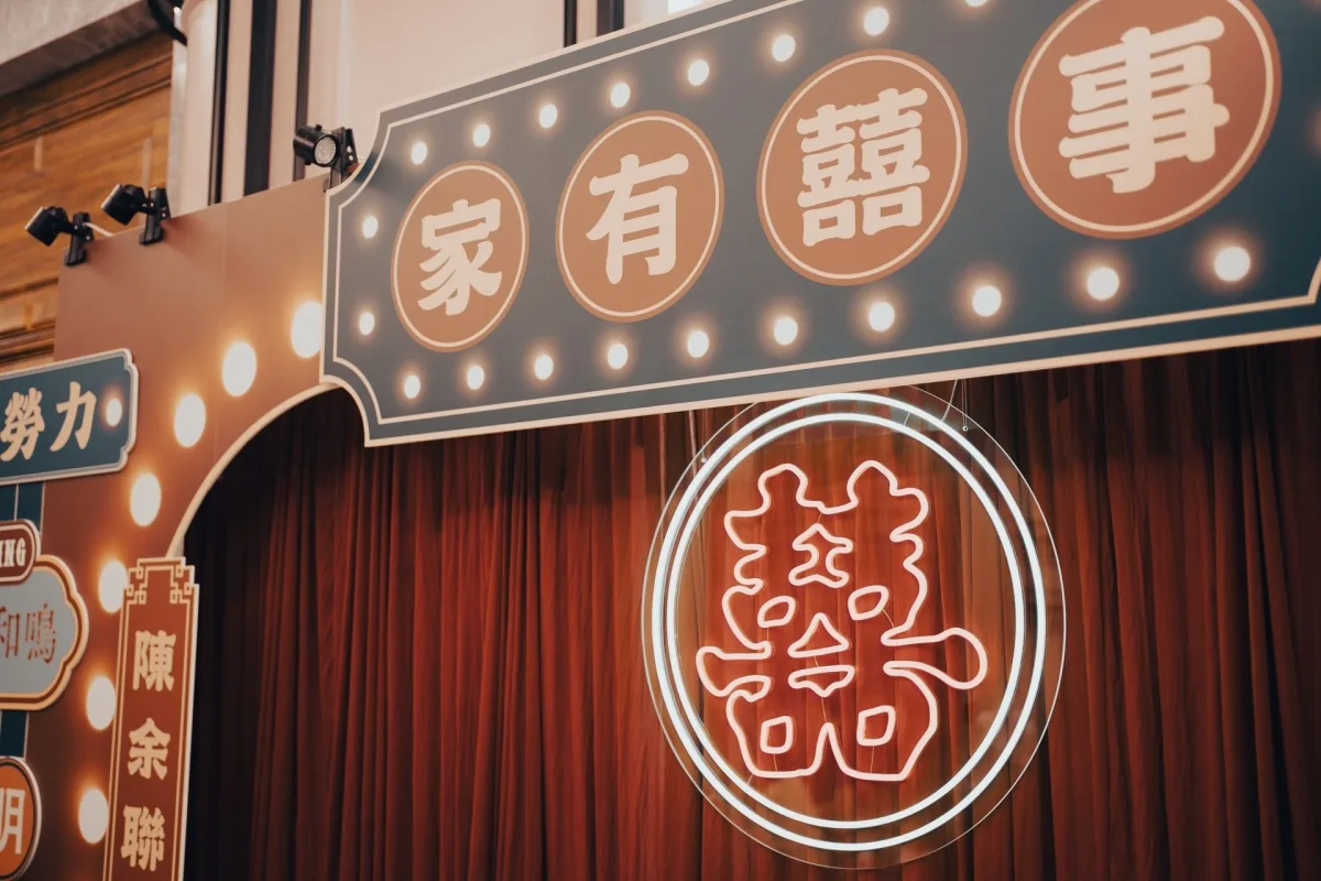 策略: 家有囍事 婚禮佈景，紅色幕簾與雙囍霓虹燈，色調溫馨喜慶。