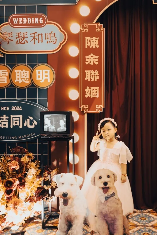 溫馨婚禮佈景，小女孩與兩隻狗在復古電視前，搭配紅棕色調與喜慶婚禮元素。