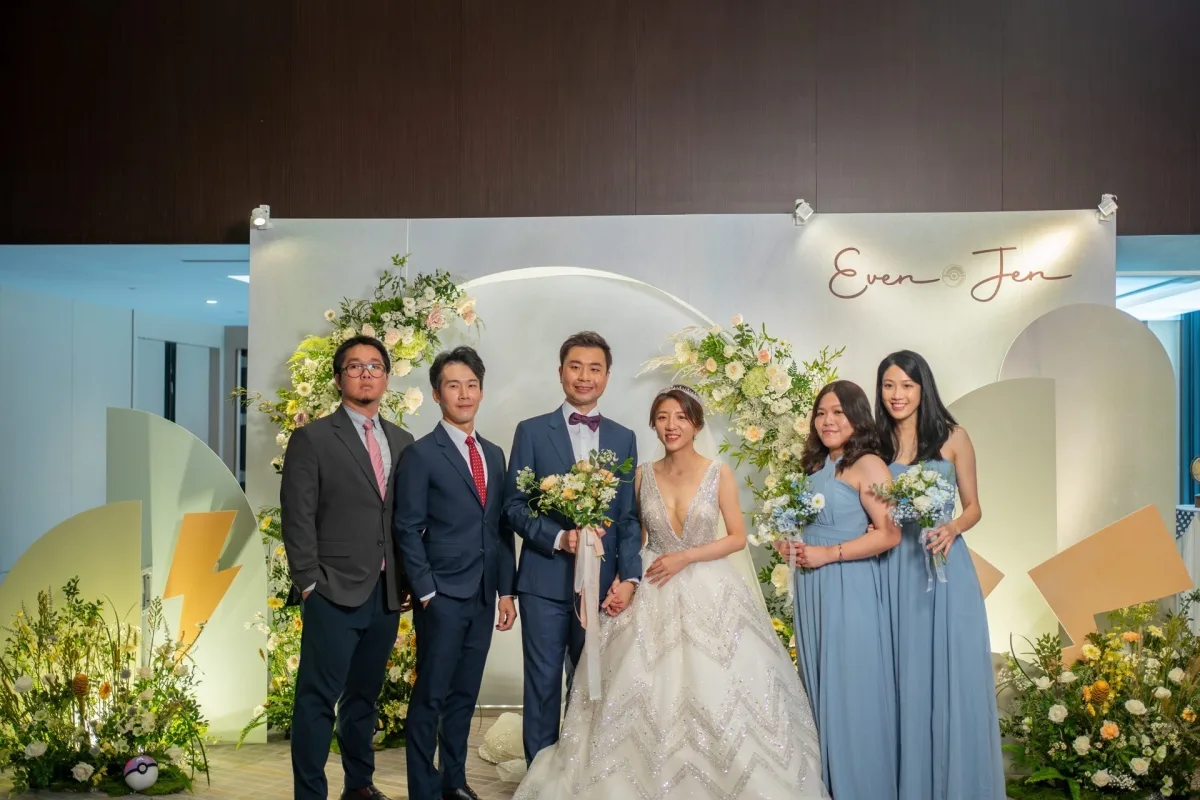 新婚夫婦與伴郎伴娘在花藝拱門前合影，色調溫暖典雅，充滿喜慶。