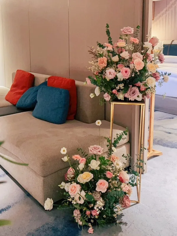 米色沙發與粉白婚禮花藝，金屬架營造柔和溫馨氛圍。