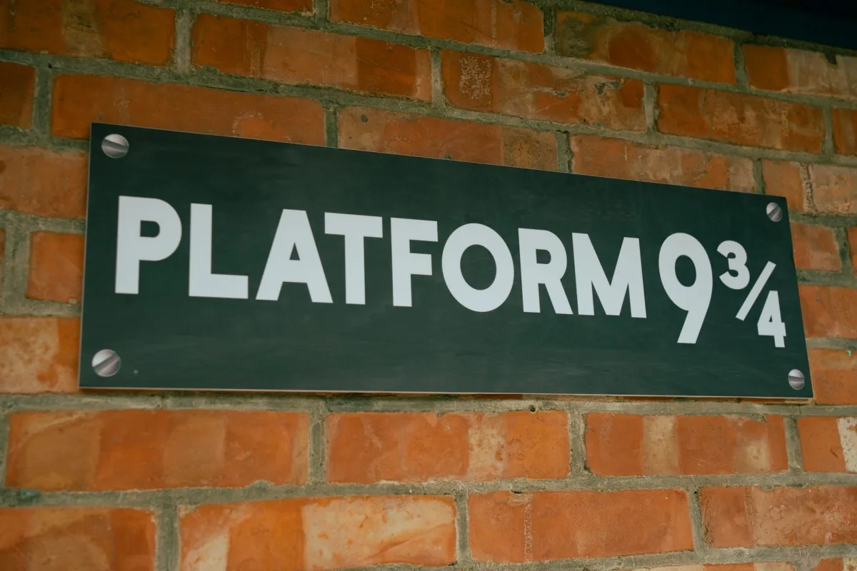 紅磚牆上掛著「PLATFORM 9 3/4」招牌，綠底白字，色調沉穩。