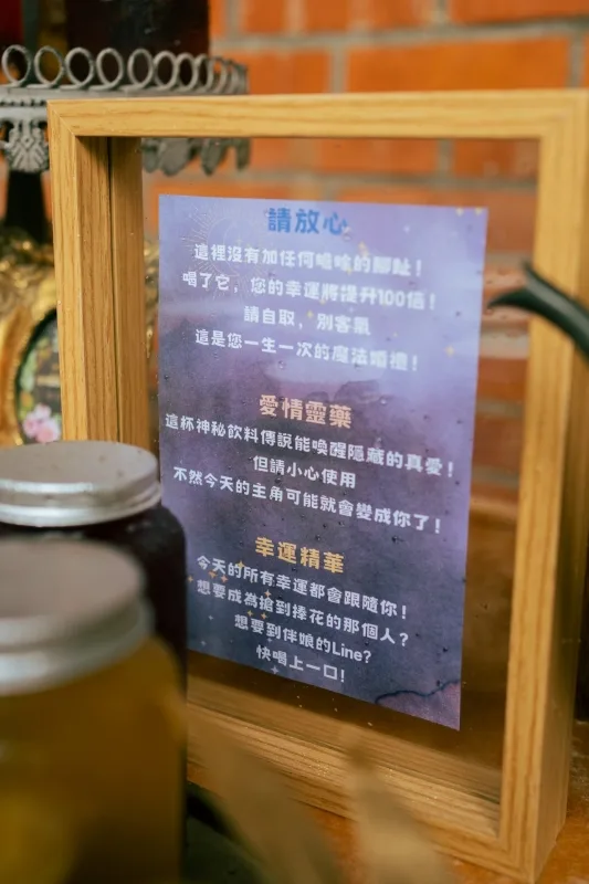 婚禮迎賓桌上的木框告示牌，紫色調愛情靈藥與幸運精華，溫馨。