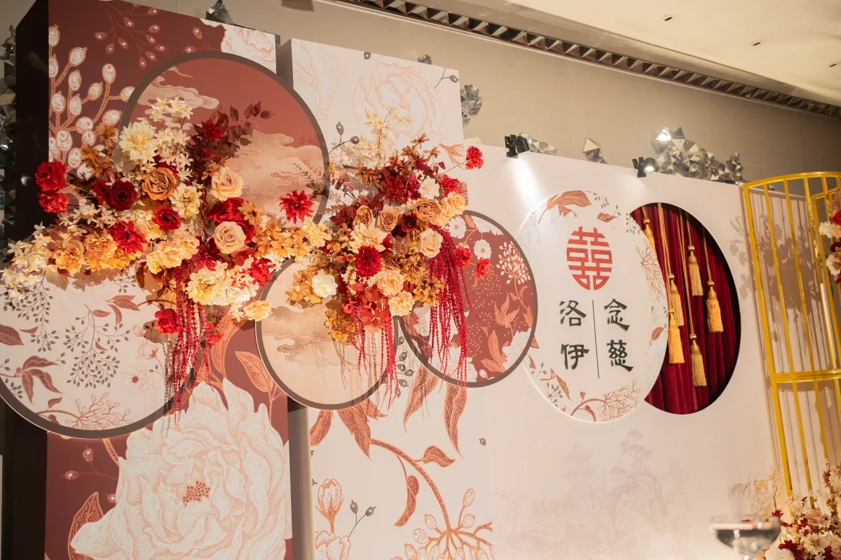 喜慶中式婚禮背板,以紅橘色系花藝裝飾,搭配雙喜字與古典圖騰