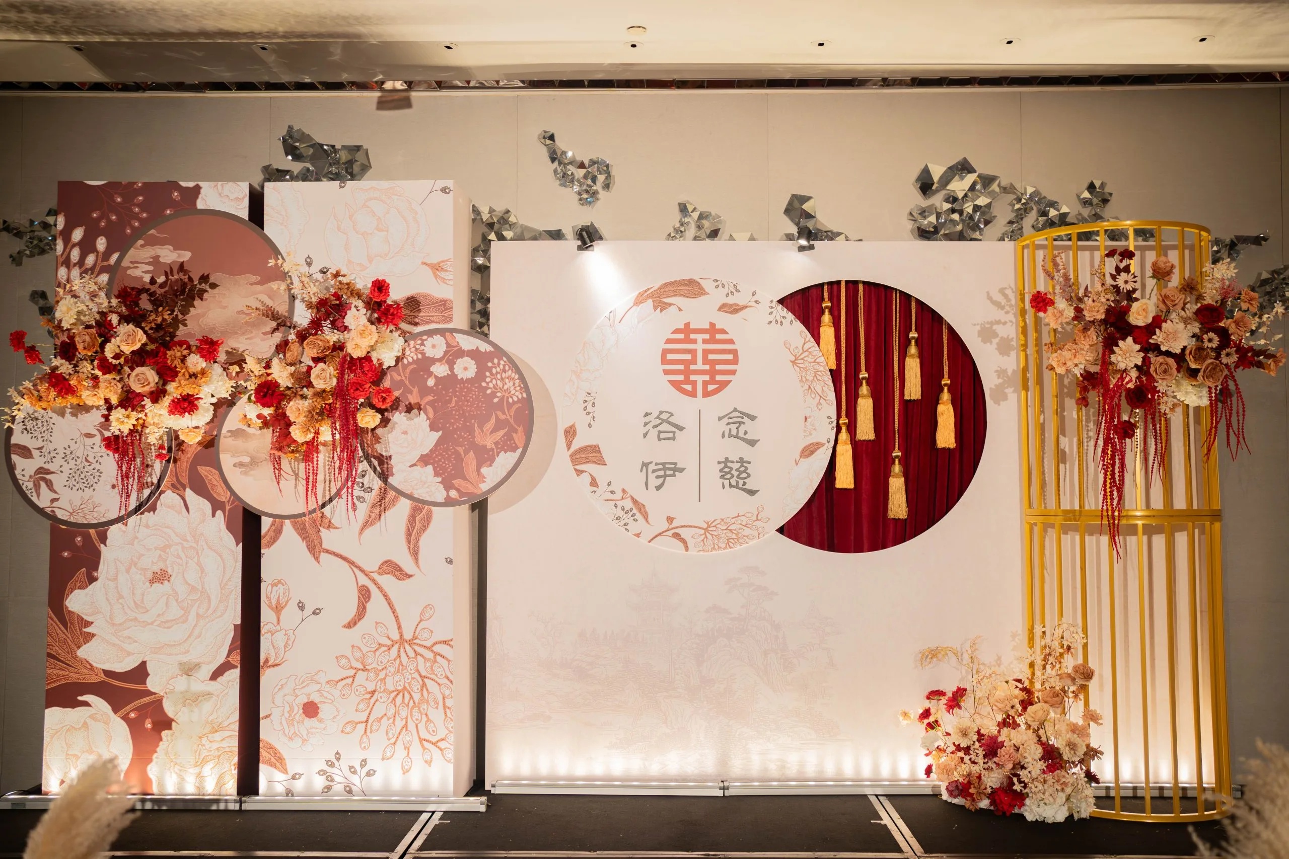 喜慶紅色婚禮背板，金囍字、鮮花與流蘇裝飾，溫馨典雅。