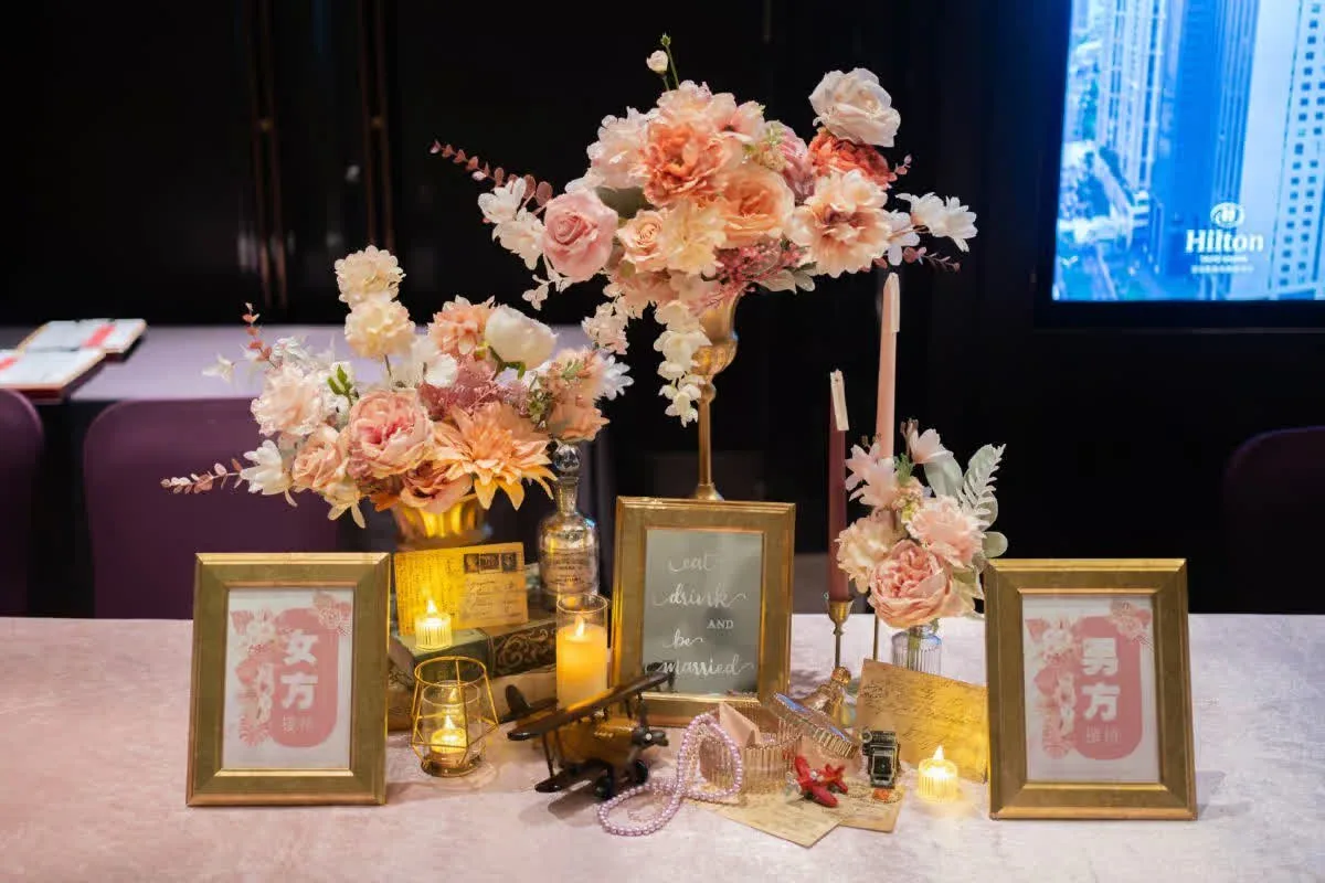 雅緻婚宴佈置，蜜桃粉花藝、金色相框與燭光，浪漫溫馨。