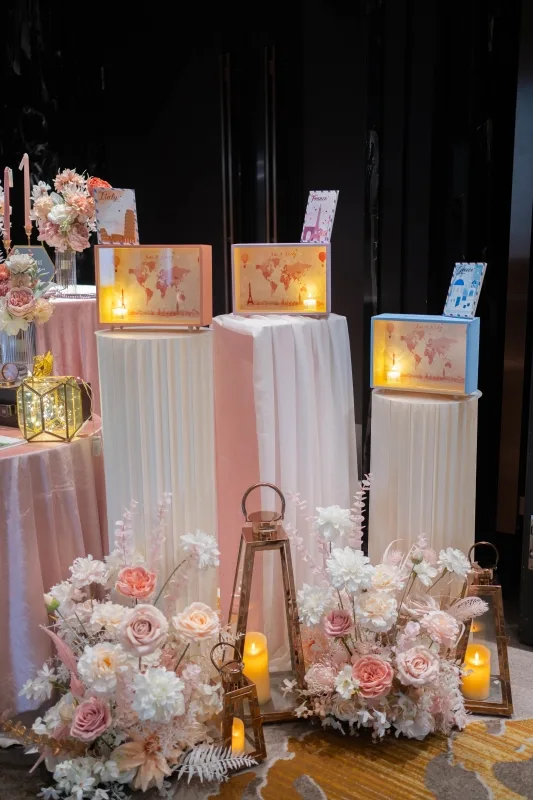 婚禮佈景：粉白花藝、燭光燈籠與世界地圖裝飾，呈現溫馨浪漫氛圍。