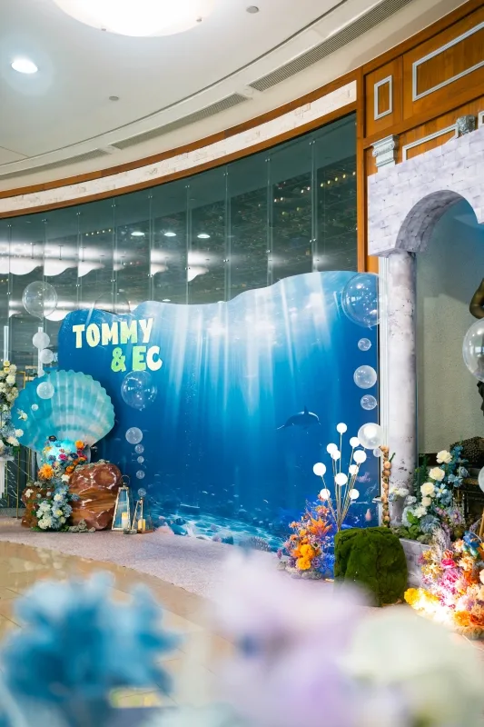 浪漫海洋婚禮背板,藍色調,海豚、珊瑚、花卉與「TOMMY & EC」字樣。