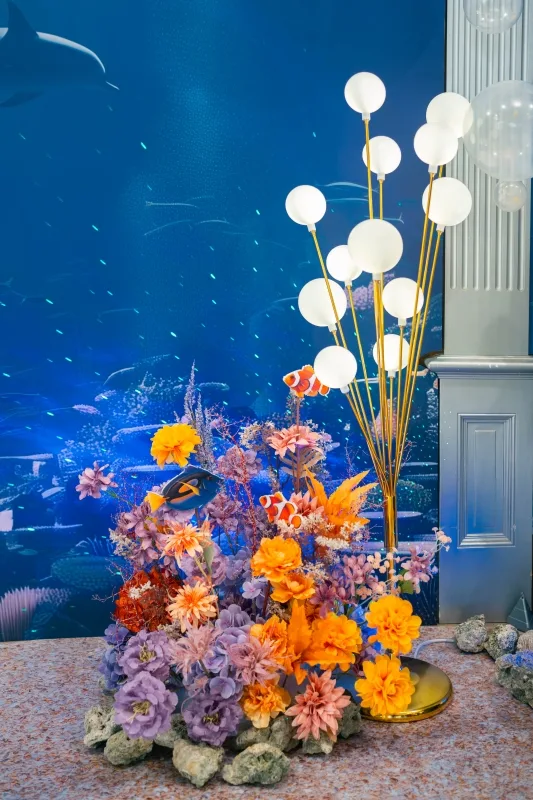 藍色海底婚禮佈景,熱帶魚穿梭繽紛花叢,搭配優雅球形燈飾。