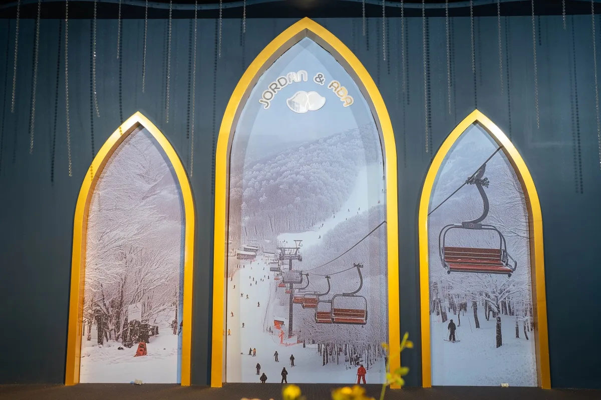 金色拱門內是冬季滑雪場景，藍灰色背景點綴水鑽，中央寫著JORDAN & ADA，色彩冷暖對比，充滿浪漫。