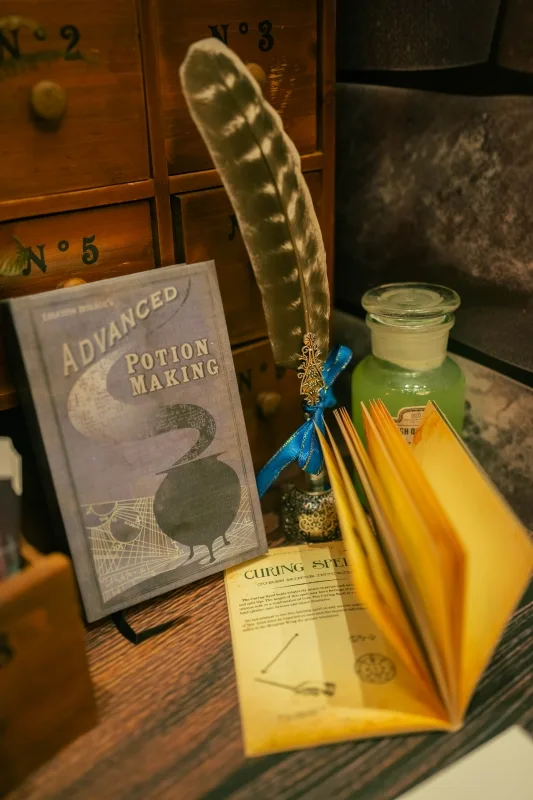 一本魔藥學書、羽毛筆、藥水瓶與魔法書,呈現神秘復古的深色調。