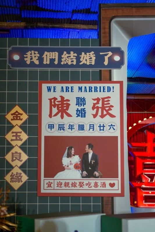 婚禮現場裝飾，紅色喜氣海報與金玉良緣掛飾，藍綠色調。