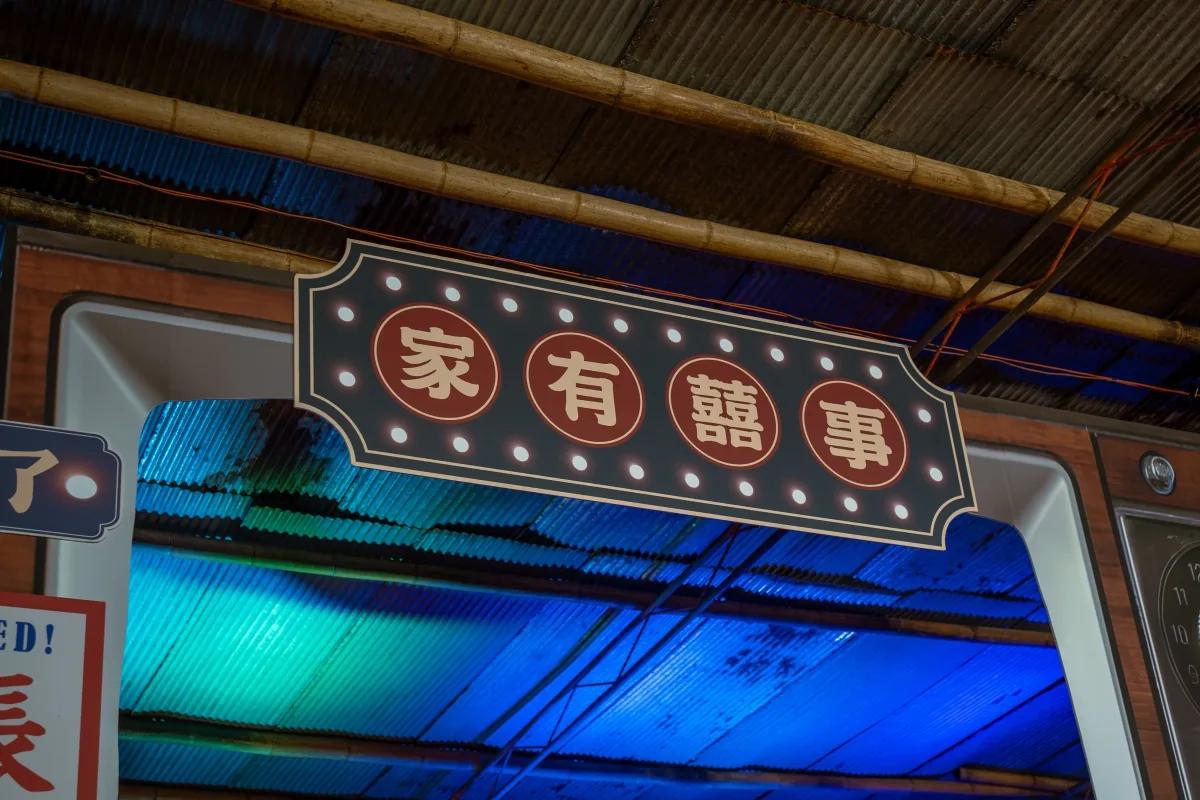 喜慶招牌「家有囍事」，紅字白光點綴，藍綠色調波浪屋頂，充滿傳統喜悅。