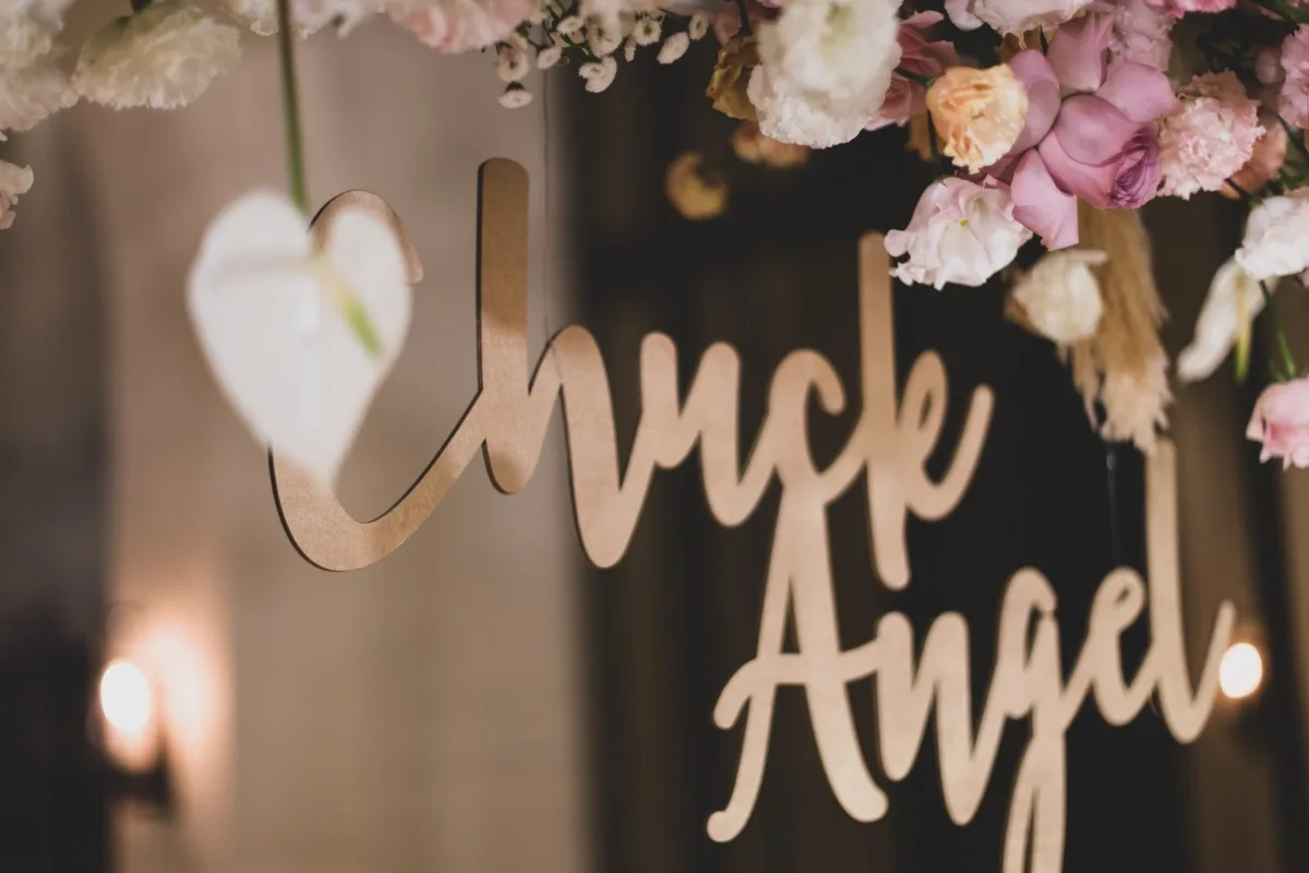 木製 Chuck & Angel 婚禮標誌，點綴粉白花卉與心形海芋，暖色調浪漫。
