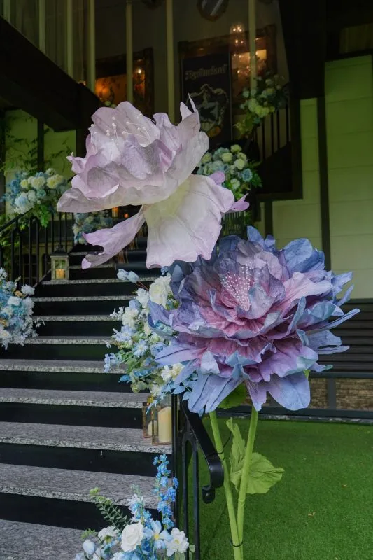 樓梯旁夢幻藍紫色巨型花卉與燭光，浪漫婚禮佈置。