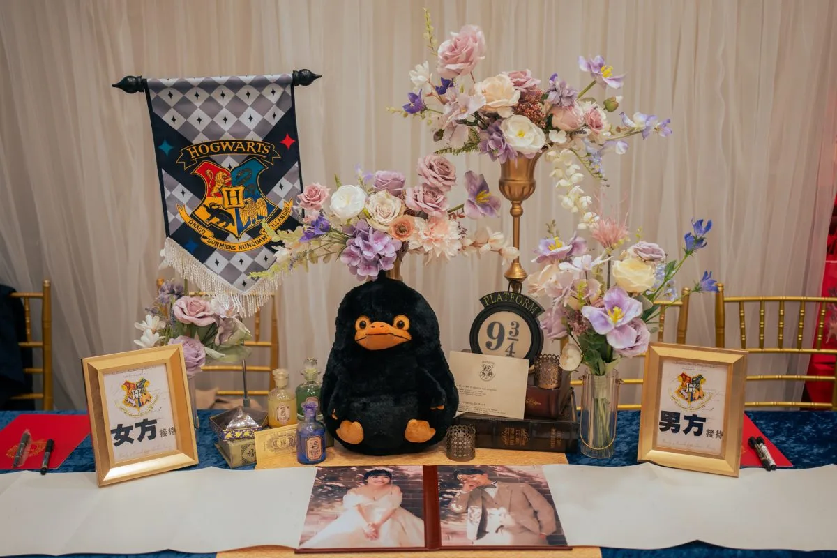 哈利波特主題婚禮接待桌，粉紫花藝、嗅嗅玩偶與金框，奇幻溫馨。