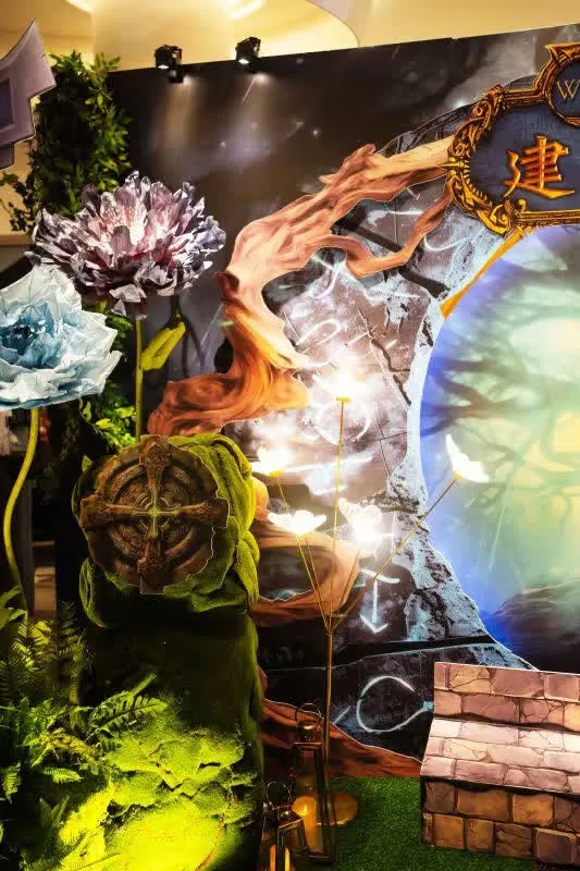 神秘森林婚禮佈景,有藍紫花朵、發光蝴蝶、綠色雕塑與溫暖燈光,色調柔和。
