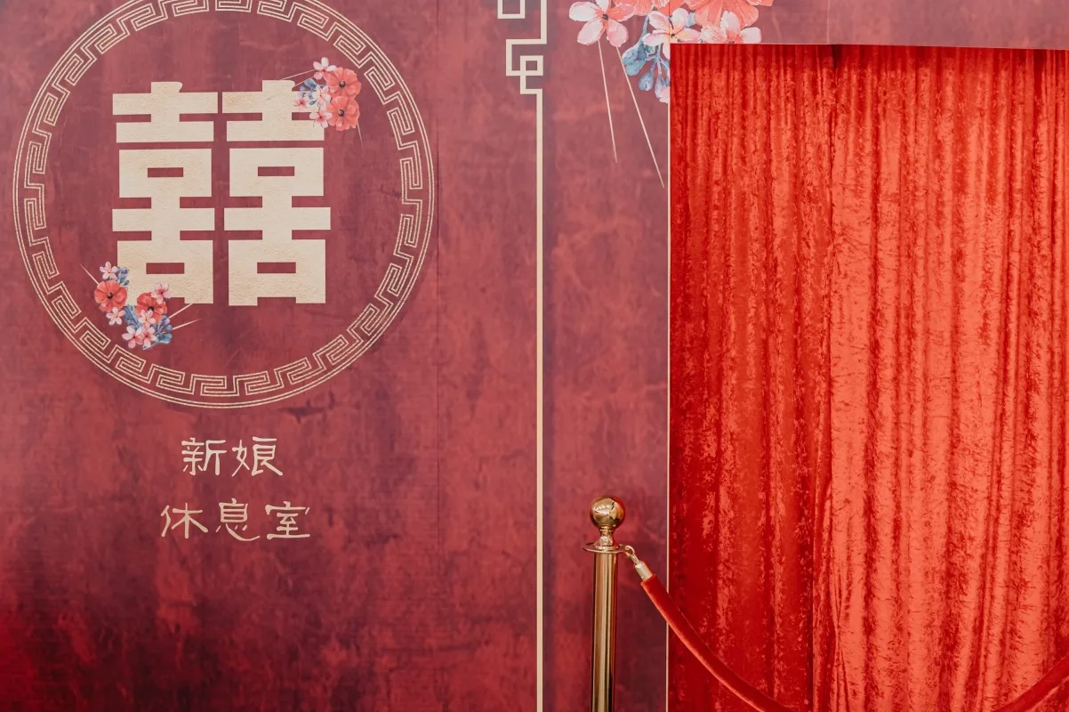 大紅婚禮背板，囍字、花卉圖案與新娘休息室標示，金紅喜氣。
